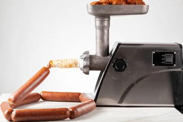 Close up isolated image of homemade sucuk or Sausage that is being stuffed into casing using electrical stuffer device.