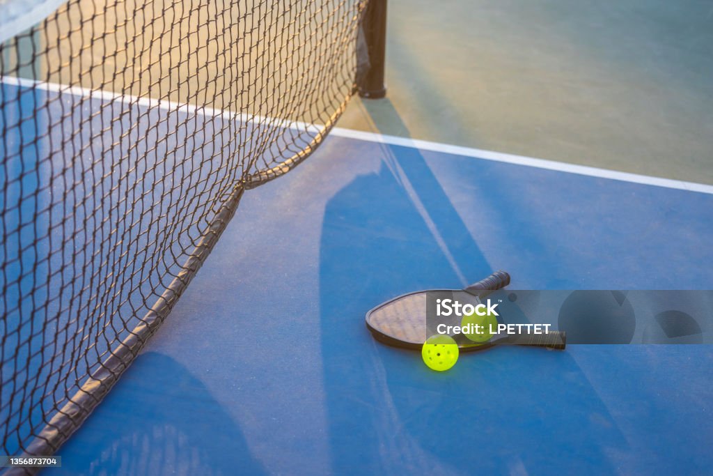 Pickeball Pickle ball paddle and ball on a blue pickle ball court Pickleball Stock Photo