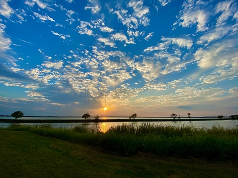 Sunset with brilliant blue sky and many small clouds over water (Lake Overholser; Oklahoma City)