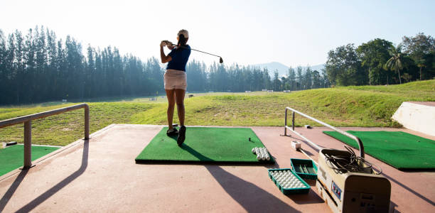istock Young woman practices her golf swing on driving range, view from behind.Sport Concept 1356886036