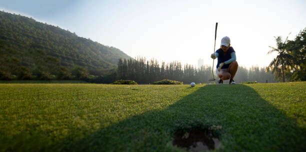 jogadora de golfe asiática esportiva agachada e estudar o verde antes de colocar tiro . conceito esportivo e saudável - golf women female concentration - fotografias e filmes do acervo