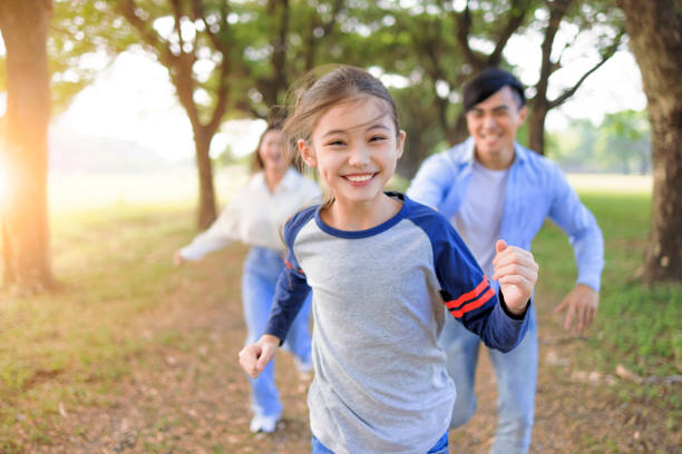 happy family courant et jouant ensemble dans le parc - child family offspring fun photos et images de collection