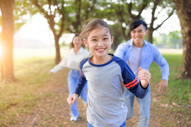happy family corre e gioca insieme nel parco - asian ethnicity women young adult cheerful foto e immagini stock