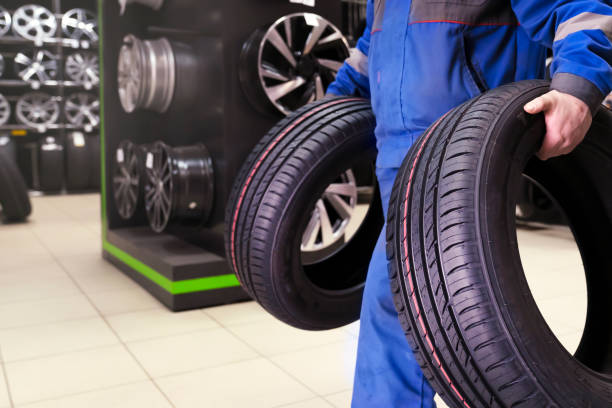 the buyer carries new tires to the exit of the tire shop, or the tire fitter master carries the wheels for a seasonal change of tire wheels for safe driving in winter or summer stock photo