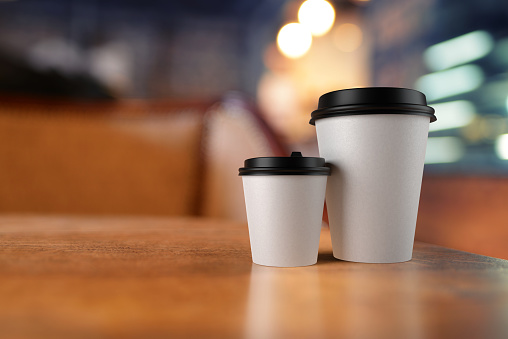 White take away cups with coffee on bokeh background, mock up. 3D rendering and photo