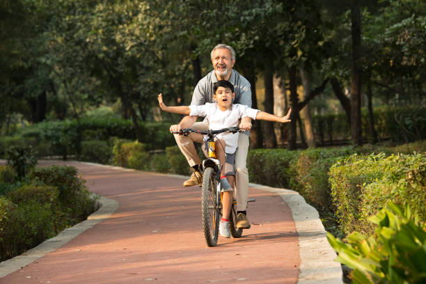 Grandfather with grandson riding bicycle at park stock photo