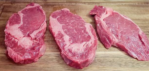 istock Raw steaks with seasoning on dark wooden background 1356897850