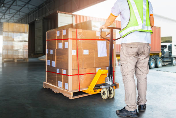 Worker Courier Using Hand Pallet Jack Unloading Package Boxes into Cargo Container. Delivery service. Truck Loading at Dock Warehouse. Supply Chain Shipments. Shipping Cargo Transport. Logistics Worker Courier Using Hand Pallet Jack Unloading Package Boxes into Cargo Container. Delivery service. Truck Loading at Dock Warehouse. Supply Chain Shipments. Shipping Cargo Transport. Logistics loading bay stock pictures, royalty-free photos & images