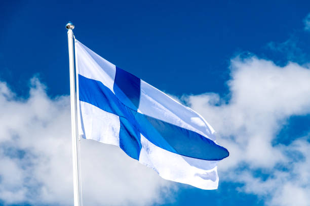 finland national flag waving on blue sky. flag of finland also called siniristilippu. - finsk flagga bildbanksfoton och bilder