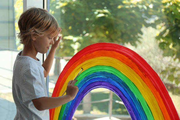 istock Little boy drawing rainbow on window. Stay at home concept 1356906862