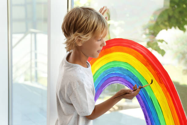 istock Little boy drawing rainbow on window. Stay at home concept 1356906949