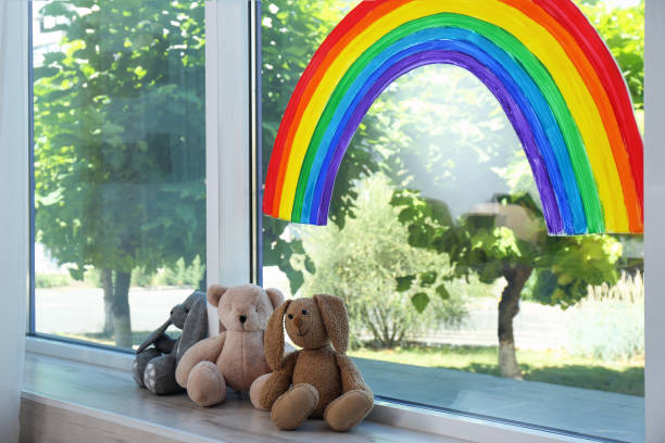 窓に虹の絵と室内のおもちゃ。家にいる概念 - epidemic paint virus illness ストックフォトと画像