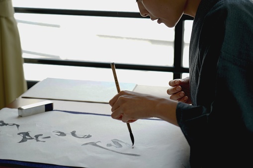 Japanese calligraphy set - Japanese woman in Kimono writing a character with a brush