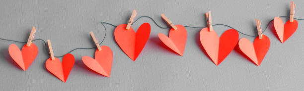 Paper hearts on a clothesline with wooden clothespins stock photo