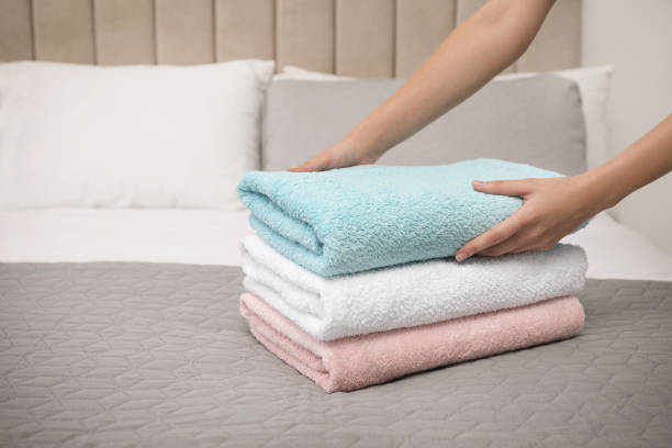 istock Woman folding soft clean terry towels on bed, closeup 1356910302