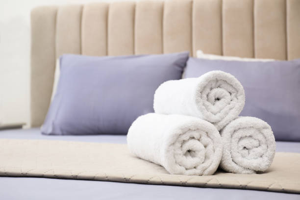 istock Rolled soft clean towels on bed indoors. Space for text 1356910376