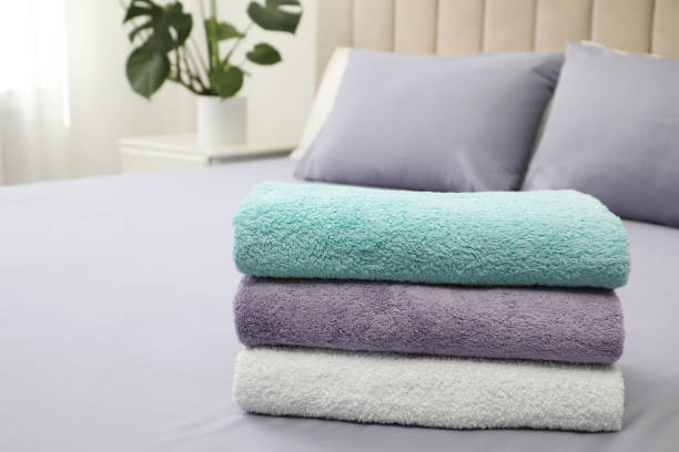 istock Stack of clean towels on bed indoors 1356910508