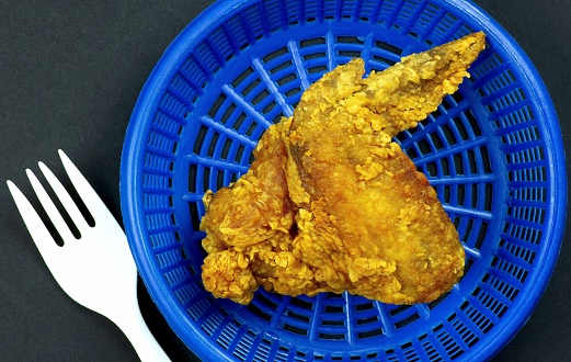 Fried Chicken wing in blue basket and white plastic fork.