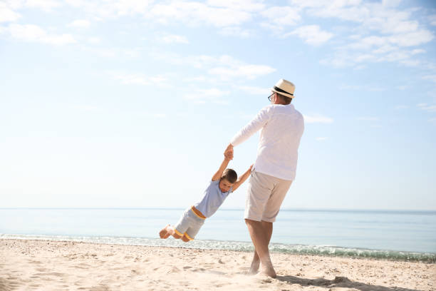istock Grandfather playing with little boy on sea beach 1356910691