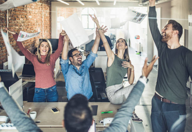 istock Large group of happy colleagues throwing reports in the office. 1356913972