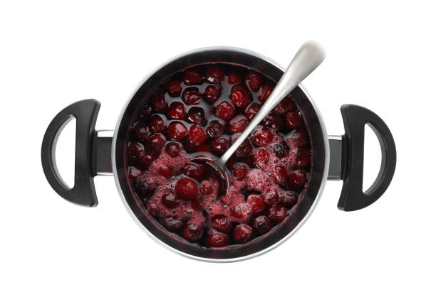 istock Pot with cherries in sugar syrup on white background, top view. Making delicious jam 1356915098