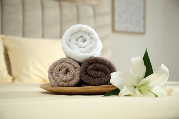 istock Rolled clean towels and flower on bed indoors 1356915614