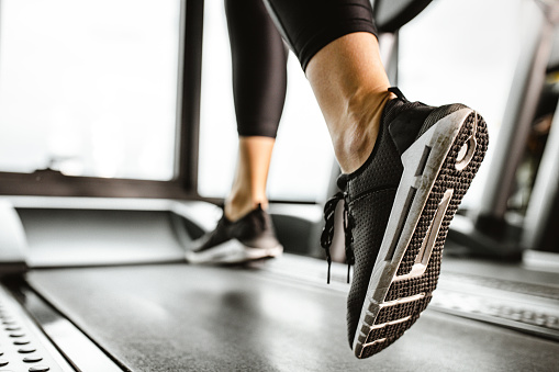 istock Close up of unrecognizable athlete running on a treadmill in a gym. 1356917258