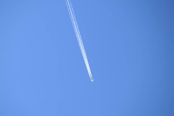 istock Distant passenger jet plane flying on high altitude on clear blue sky leaving white smoke trace of contrail behind. Air transportation concept. 1356918848