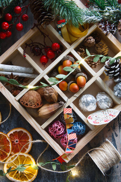 istock Natural materials for home made garlad - dry orange chips, nuts, arcons, berries, cinnamon sticks and pine cones, eco friendly, on wooden table with lights and fur tree branch, flat lay 1356924346