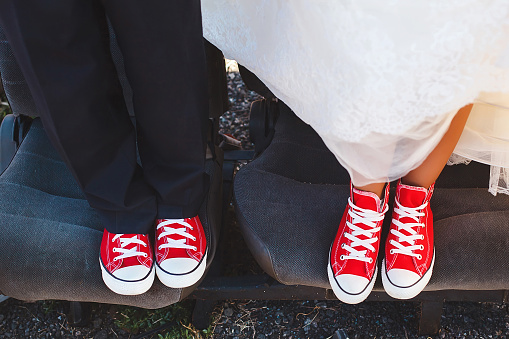 The bride and groom in red sneakers in the junkyard car\