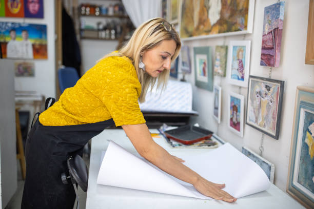 istock Female lithography artists, bending the paper, preparing it for printmaking technique 1356927262
