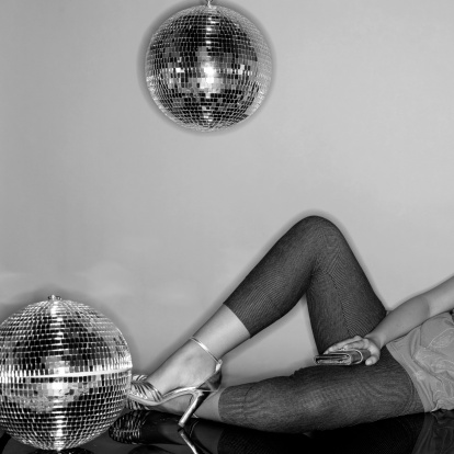 woman laying on the floor in gray background with two disco balls