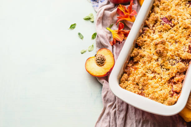 istock Yummy peach crumble dessert in baking pan on light background , top view. 1356928405
