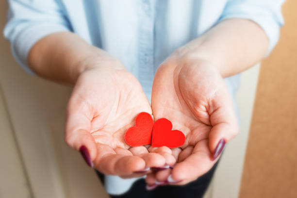 istock female hands hold two red paper hearts selective focus. 1356929026