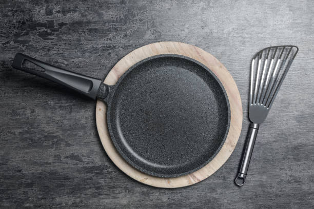 istock Cooking pan and slotted turner on grey table, flat lay. Kitchen utensils 1356931528