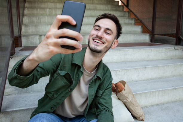 istock Smiling young man using mobile phone outdoors 1356933479