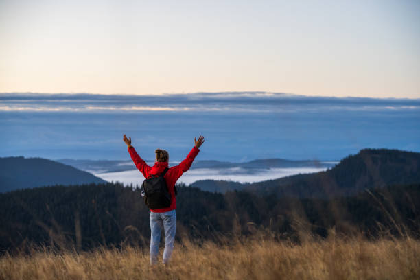 istock Female hiker relaxes on grassy mountain ridge 1356935922