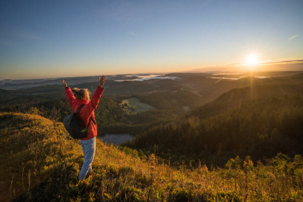 istock Female hiker relaxes on grassy mountain ridge 1356935995