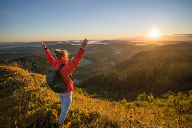 Female hiker relaxes on grassy mountain ridge
