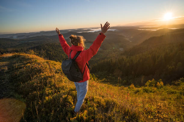 istock Female hiker relaxes on grassy mountain ridge 1356936002