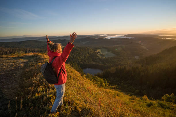 istock Female hiker relaxes on grassy mountain ridge 1356936004