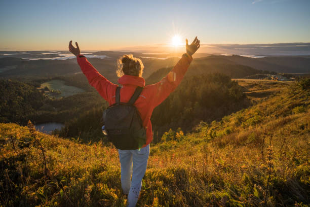 istock Female hiker relaxes on grassy mountain ridge 1356936007