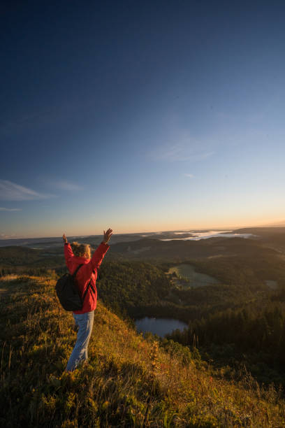 istock Female hiker relaxes on grassy mountain ridge 1356936015