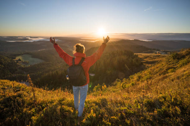 istock Female hiker relaxes on grassy mountain ridge 1356936016