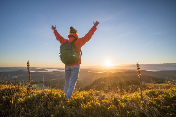 istock Female hiker relaxes on grassy mountain ridge 1356936022