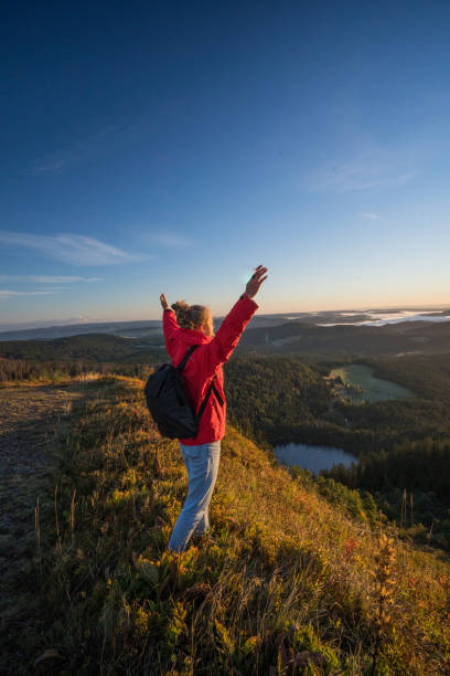 istock Female hiker relaxes on grassy mountain ridge 1356936024
