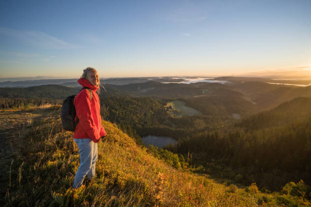 istock Female hiker relaxes on grassy mountain ridge 1356936027