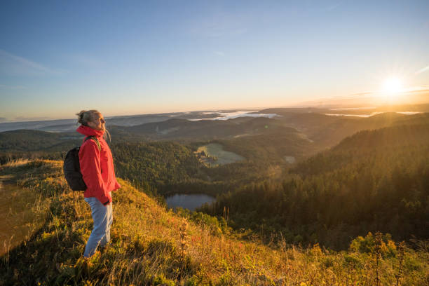 istock Female hiker relaxes on grassy mountain ridge 1356936033