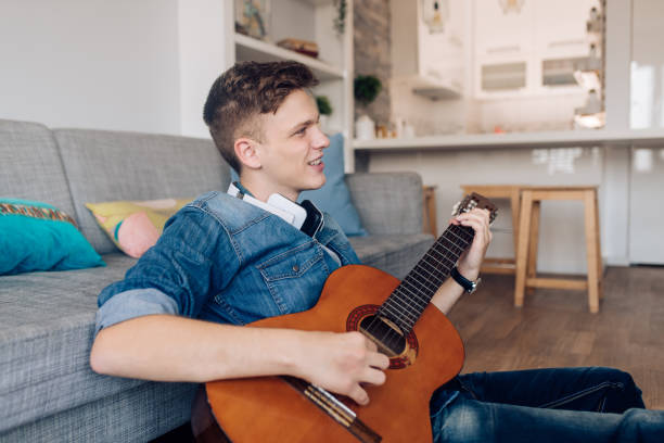 istock Young man playing a guitar and enjoying at home 1356937450