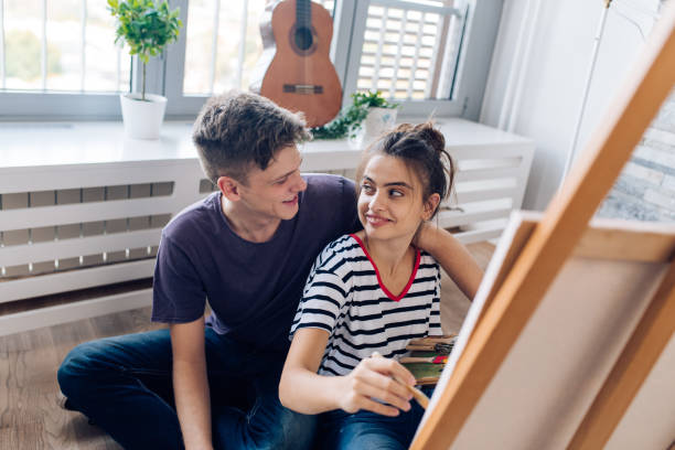 istock Young man enjoying with his girlfriend while she's painting 1356937458